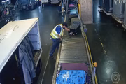 Pelas câmeras internas do aeroporto de Guarulhos, um funcionário seleciona a mala preta das jovens
