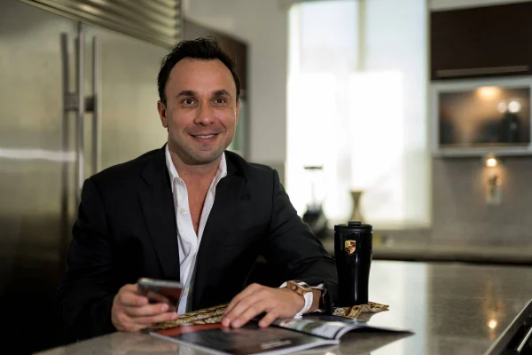 Fotografia colorida mostrando o advogado Daniel Toledo usando blazer preto e sentado em mesa de cozinha-Metrópoles