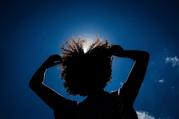 Silhueta de mulher negra com as mãos em cabelo crespo