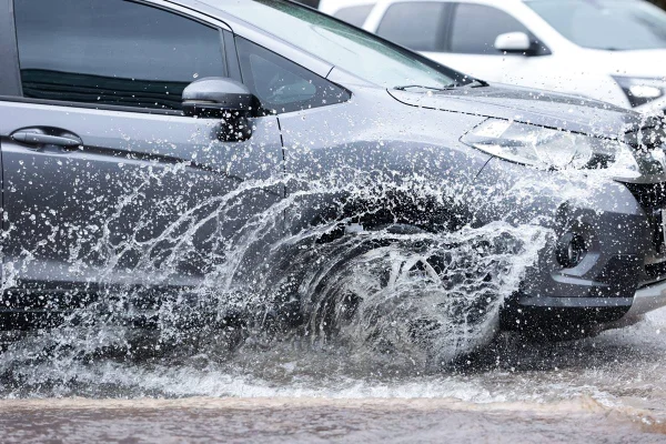 Carro anda em rua alagada após chuva