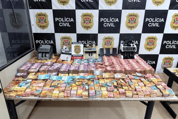Imagem colorida de centenas de milhares de notas de dinheiro em cima de uma mesa da Polícia Civil - Metrópoles