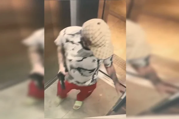homem de boné dentro de elevado com arma de fogo na mão