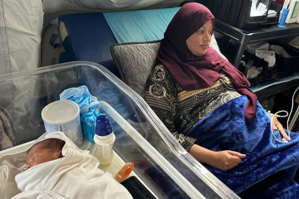 Imagem colorida, uma mulher deitada ao lado de um bebê - Metrópoles