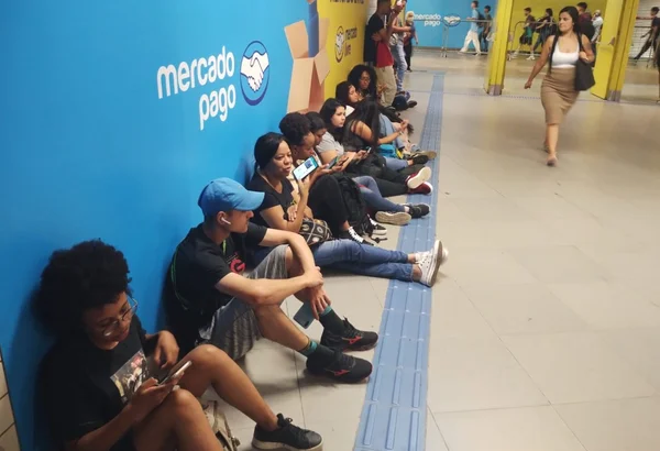 Imagem colorida de pessoas sentadas no chão esperando o fim da greve no Metrô-SP