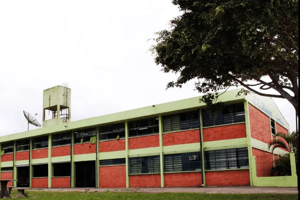 Imagem colorida de uma escola pintada de verde e tijolos - Metrópoles
