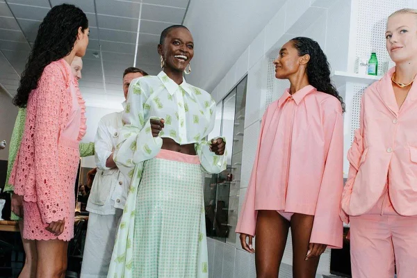 Modelos riem usando roupas com tons de rosa e branco