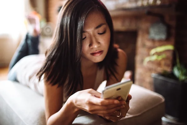 Mulher mexendo nas redes sociais em seu telefone enquanto está em casa