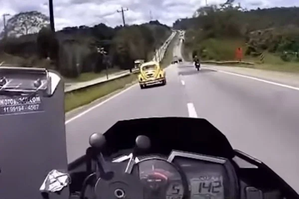 Imagem colorida mostra fusca amarelo em fuga de uma moto, que registra a velocidade de 142 km/h - Metrópoles