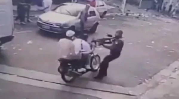 Imagem de motociclista passando por PM com fuzil - Metrópoles