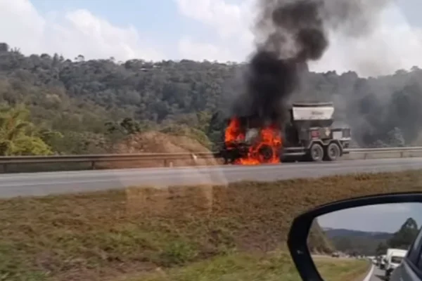 Imagem colorida de caminhão pegando fogo em rodovia. Metrópoles