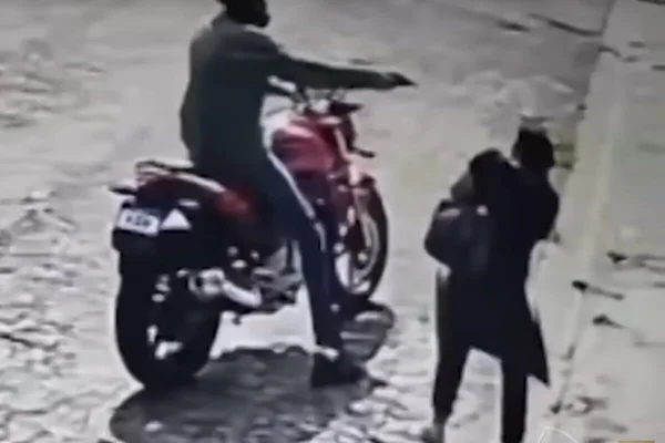 Imagem colorida de motoqueiro apontando arma em direção à cabeça de mulher - Metrópoles