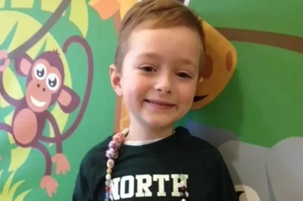 Imagem colorida de criança sorrindo para a câmera em fundo colorido com desenhos - Metrópoles