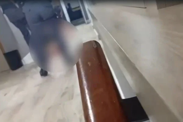 imagem colorida mostra dois policiais fardados de costas. no chão a imagem está borrada, mas é possível perceber uma terceira pessoa caída. É uma mulher que levou chutes de um agente da polícia militar (PM) - Metrópoles