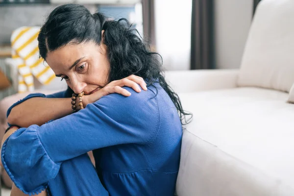 Mulher de camisa azul cansada e cabisbaixa - Metrópoles