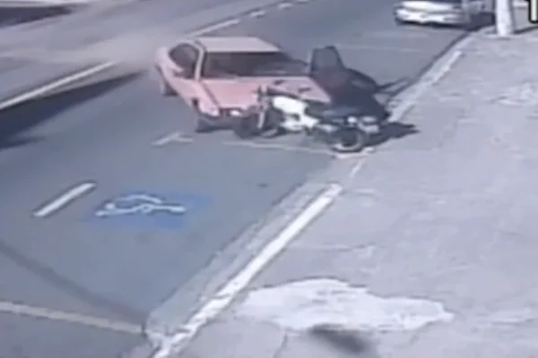 Imagem colorida de carro colidindo com moto estacionada na frente de cartório. Metrópoles