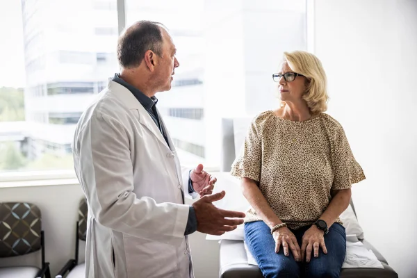 Médico sênior consultando uma mulher idosa na sala de exames - Diagnóstico com IA: entenda por que a supervisão médica é crucial