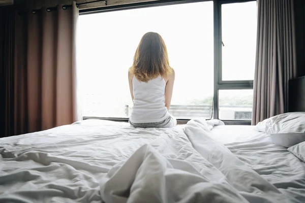 Fotografia colorida de Mulher sentada na cama -Metrópoles