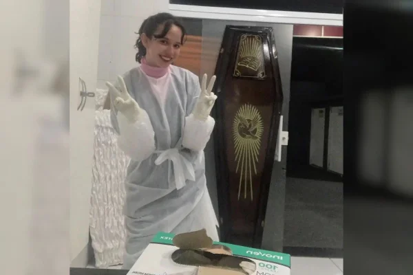 Imagem colorida de jovem uniformizada em frente a caixão
