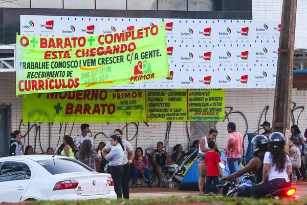 Atrás de emprego, centenas dormem na porta de mercado do DF