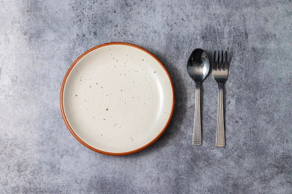 Fotografia de prato vazio com colheres ao lado. Conceito de fome, insegurança alimentar. Metrópoles
