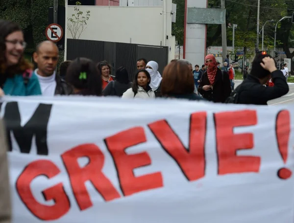 imagem colorida mostra cartaz de greve e pessoas ao fundo reajuste servidores - metrópoles