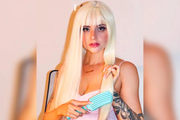 Foto colorida de mulher escovando o cabelo, encarando a cãmera - Metrópoles.