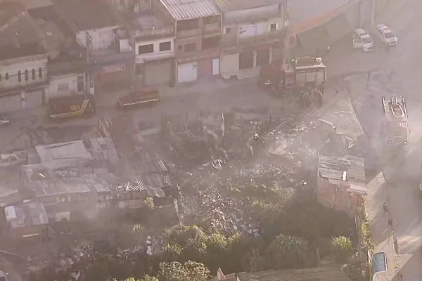 Imagem aérea colorida mostra escombros de construções de madeira carbonizadas após incêndio - Metrópoles