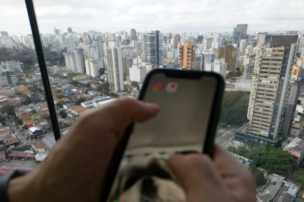 Imagem mostra celular com zona oeste da cidade de São Paulo ao fundo - Metrópoles