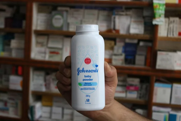 Imagem mostra uma pessoa segurando uma embalagem de talco da Johnson & Johnson - Metrópoles