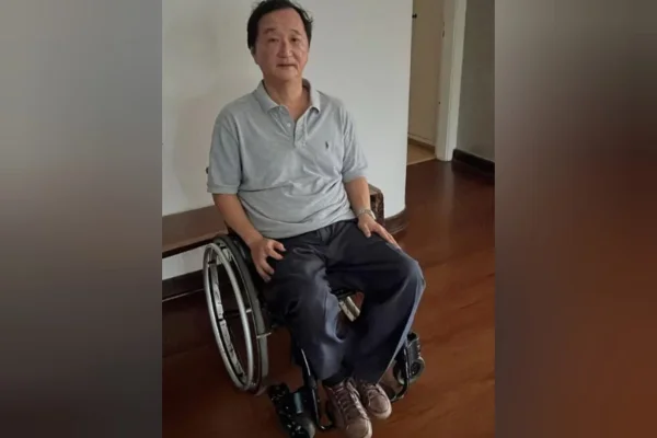 Homem branco em cadeira de rodas. Ele veste camisa polo cinza e calça escura - Metrópoles