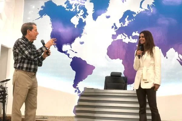Fotografia colorida de pastor e mulher em pé com mapa do mundo ao fundo