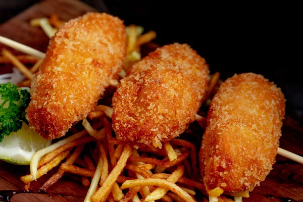 frangos empanados no espeto em cima de batatas palhas