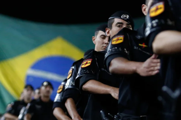 imagem colorida de Membros da Rotam Marcham em frente a bandeira nacional