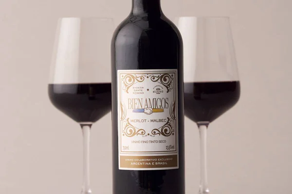 garrafa de vinho com duas taças ao fundo - metrópoles