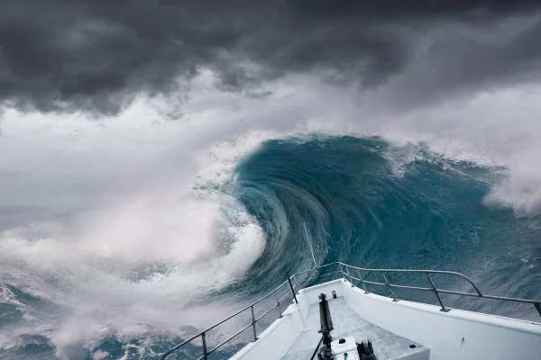 Foto colorida de onde gigante e uma proa de barco em evidência em frente à onda - Metrópoles.