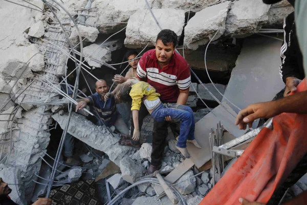 Palestino carrega uma criança morta após os ataques aéreos israelenses em um prédio de propriedade da família Abu al-Assad - metrópoles