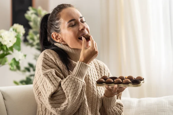 Foto colorida de mulher comendo chocolate - Metrópoles