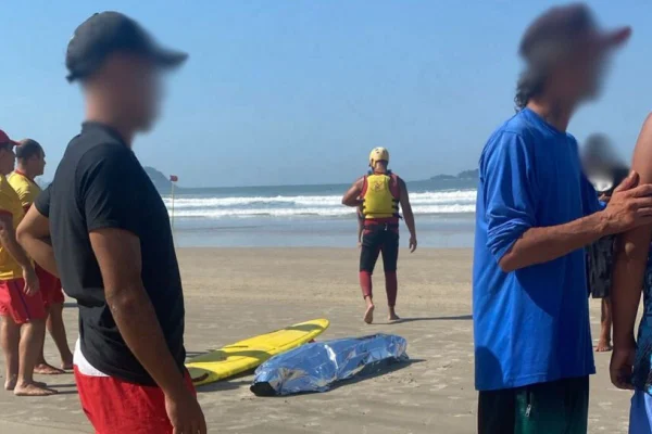 Imagem colorida mostra pessoas em volta de um corpo coberto na praia de Pitangueiras; cadáver tinha um cartão de hotel no bolso, que facilitou sua identificação - Metrópoles