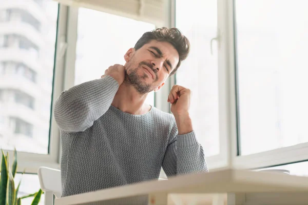 homem com mão no pescoço sinalizando dor