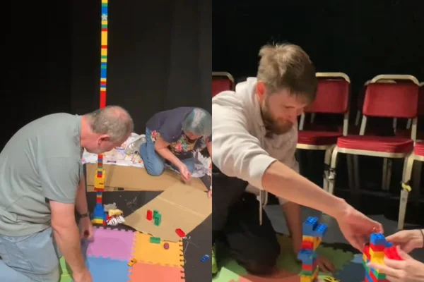 Foto colorida de dois homens brincando no chão - Metrópoles