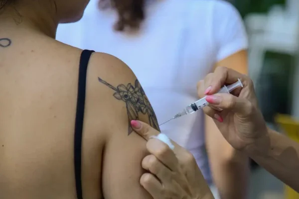foto colorida de mulher tatuada (pessoa é vista de costas) sendo vacinada contra a gripe - Metrópoles - Vacinas imunização diabetes