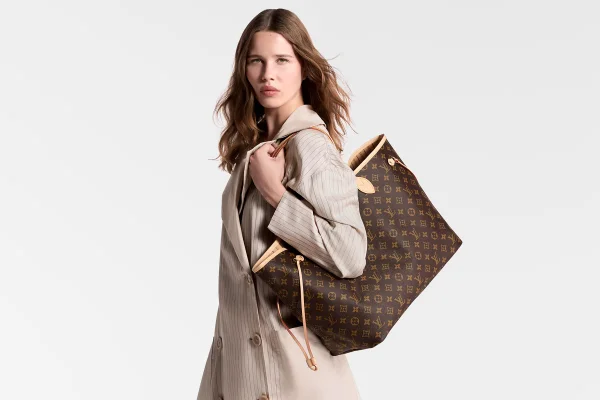 A imagem mostra uma modelo carregando uma bolsa da Louis Vuitton fotografada em fundo branco