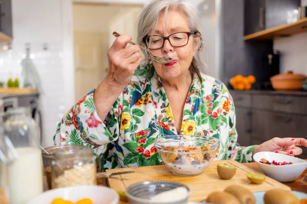Foto colorida de mulher sentada e comendo - Metrópoles