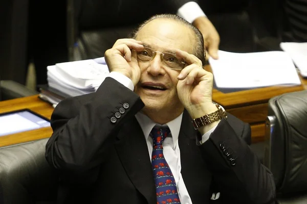 Imagem colorida mostra o ex-deputado Paulo Maluf arrumando os óculos para olhar para cima dentro da Câmara dos Deputados