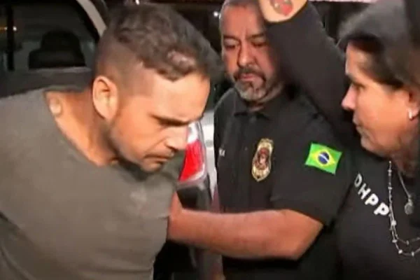 Imagem colorida de homem preso com policiais em volta; ele é suspeito de matar a menina Lara, de 12 anos, em 2022 - Metrópoles