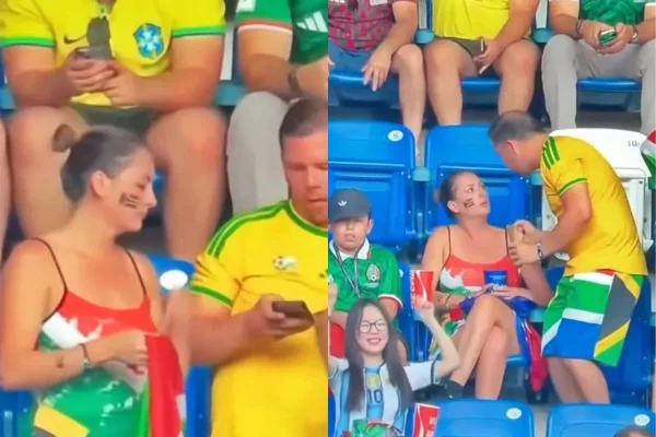 Foto colorida de casal em arquibancada de jogo da Copa