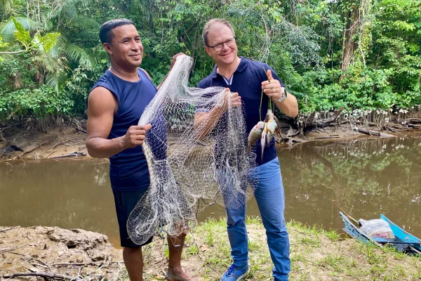 Imagem colorida, O Ministro Federal do Meio Ambiente, Carsten Schneider (à direita, SPD), mostra a um morador da comunidade quilombola de Abacatal os peixes que o professor local acabou de pescar com rede no rio- Metrópoles