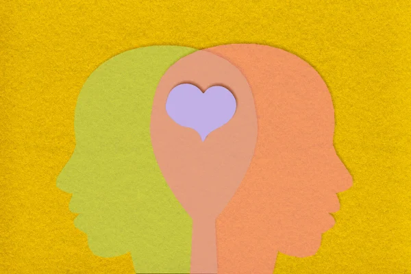 imagem de papel conceitual de amor e razão com papeis cortados em formato de cabeça e unidos por um coração - amor - metrópoles