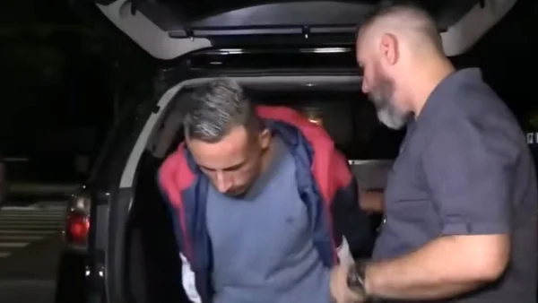 Imagem de homem com cabeça baixa saindo de viatura conduzido por policial - Metrópoles
