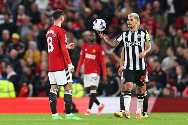 Foto colorida de Manchester United x Newcastle, com Bruno Fernandes (vermelho) e Bruno Guimarães (preto e branco) - Metrópoles